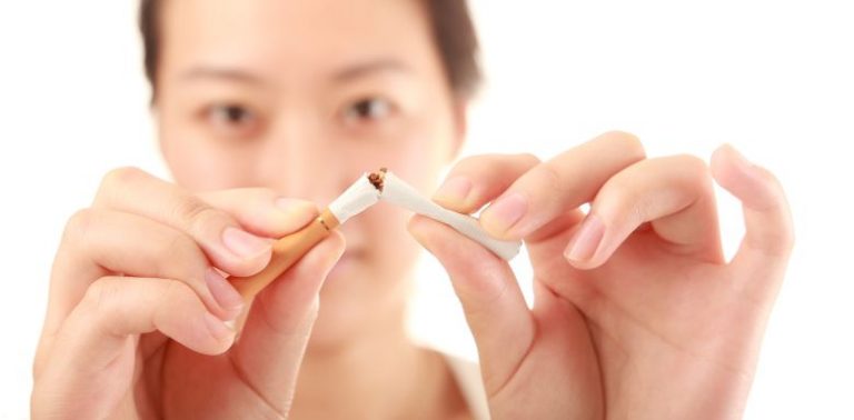 A woman breaking a cigarette in half.