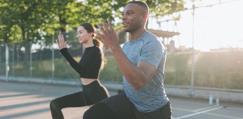 A man and woman doing stretching exercises outside.