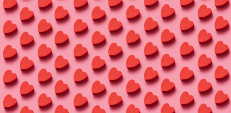 Small, illustrated red hearts in a repeating pattern on a pink background.