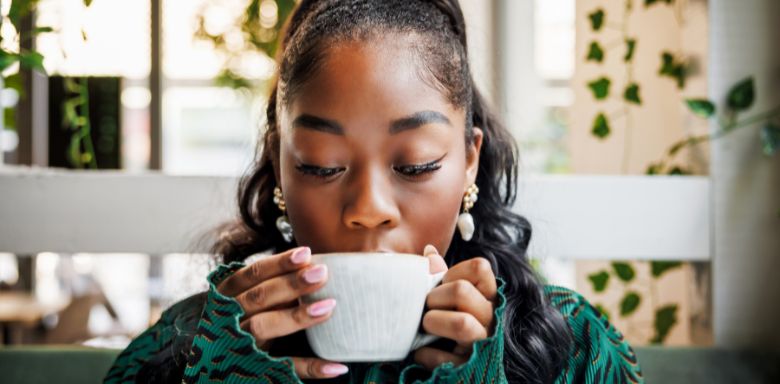 A woman drinking a mug of coffee.