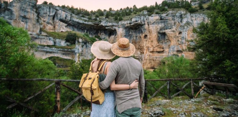 A couple with their arms around each other, looking at a rock formation.