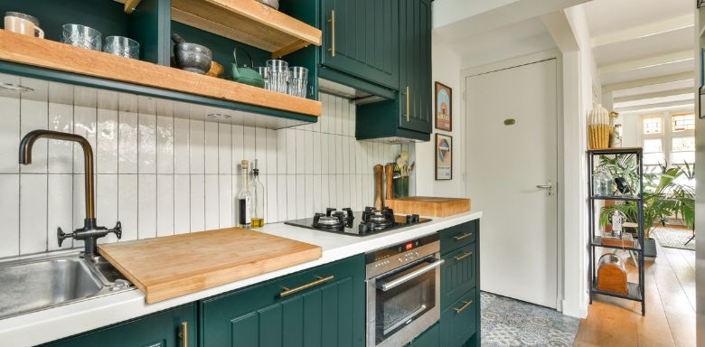 A kitchen, showing countertops, cabinets, a sink, and oven. It's very bright and clean.